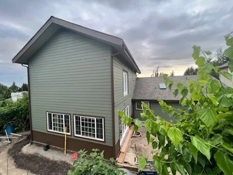 Completed two-story home addition with matching gray siding