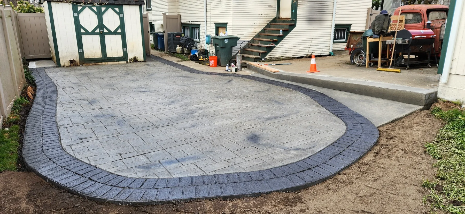 Decorative concrete driveway with a dark stamped border and curved parking edge