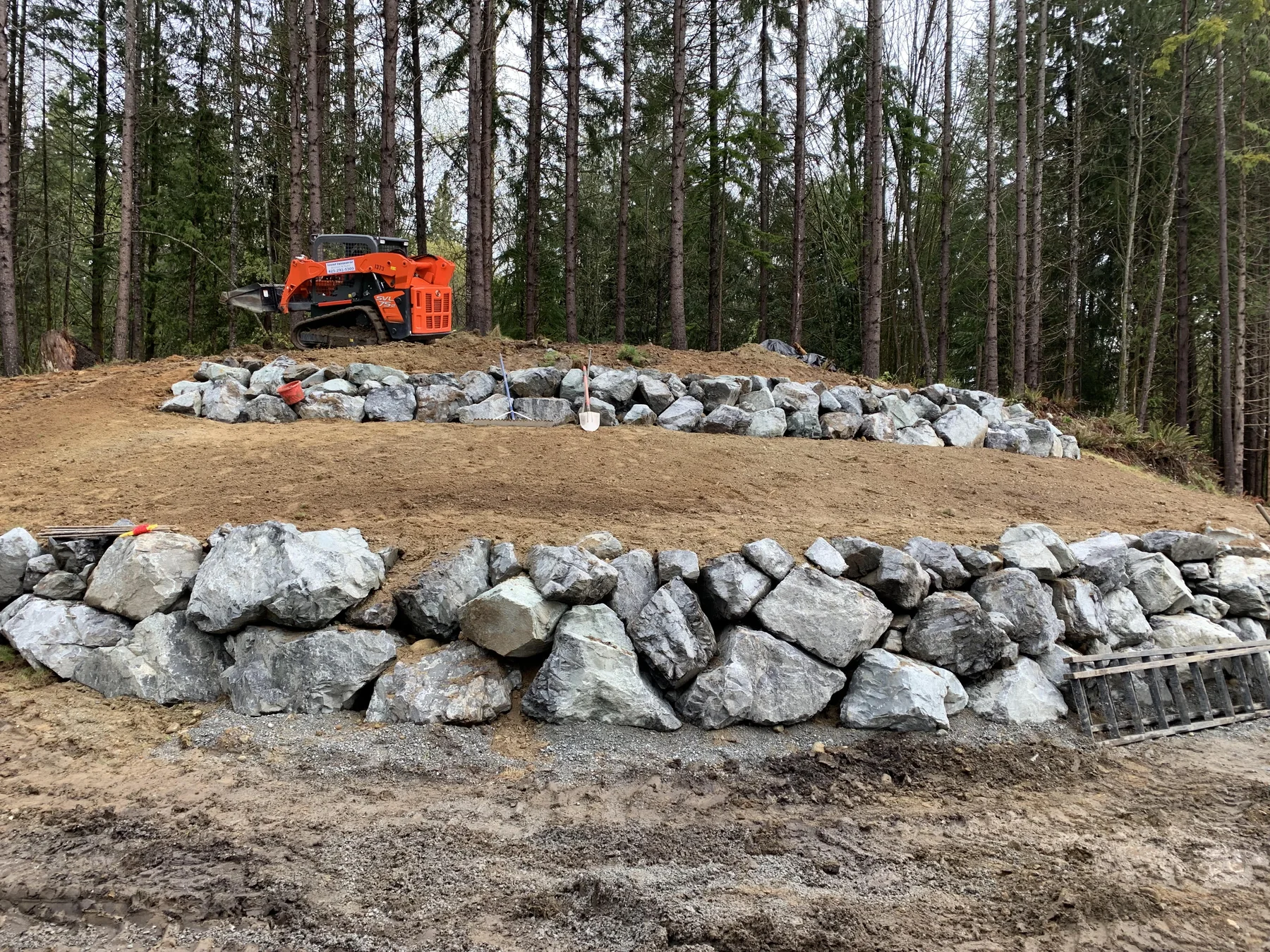 Natural rock retaining wall built into a wooded residential slope