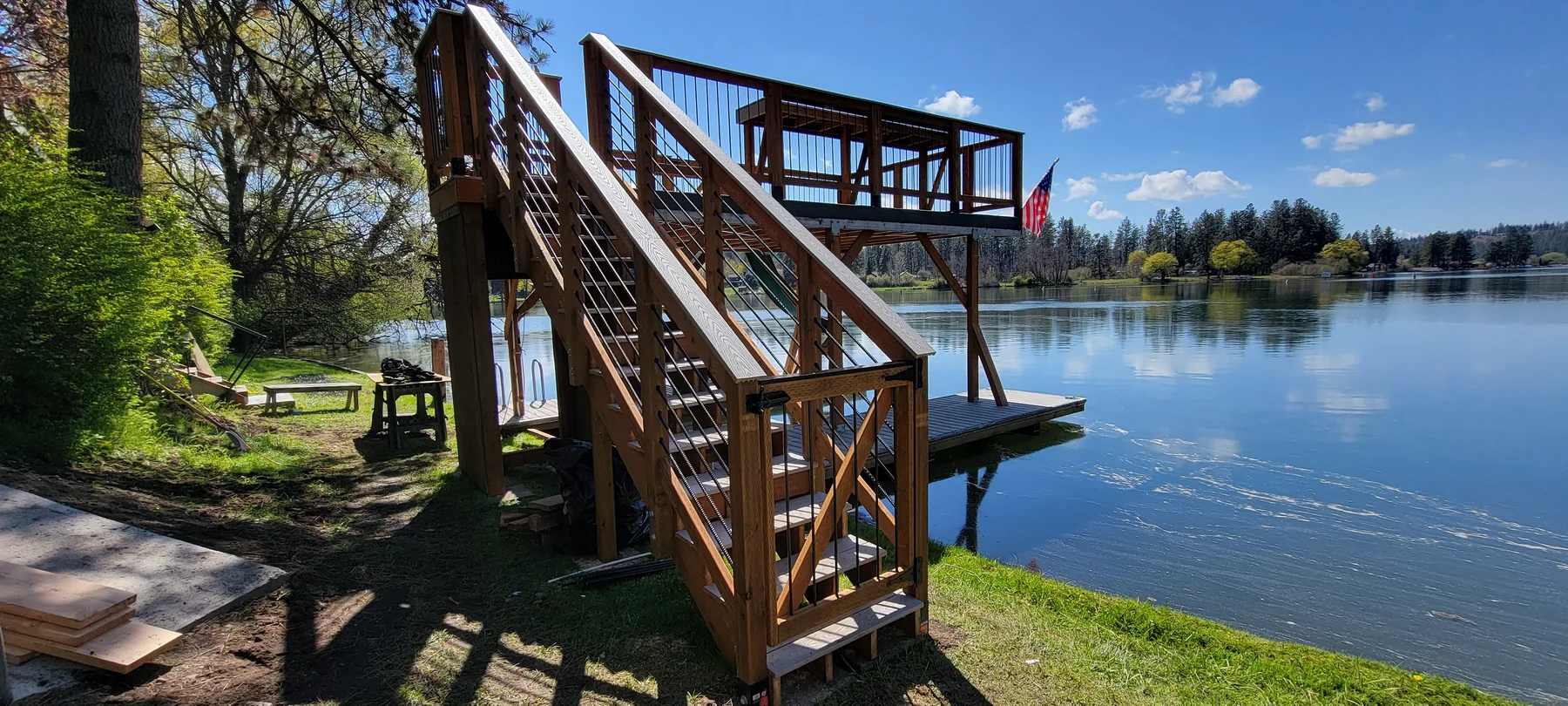 Custom two-level wood deck and stairs beside a lake