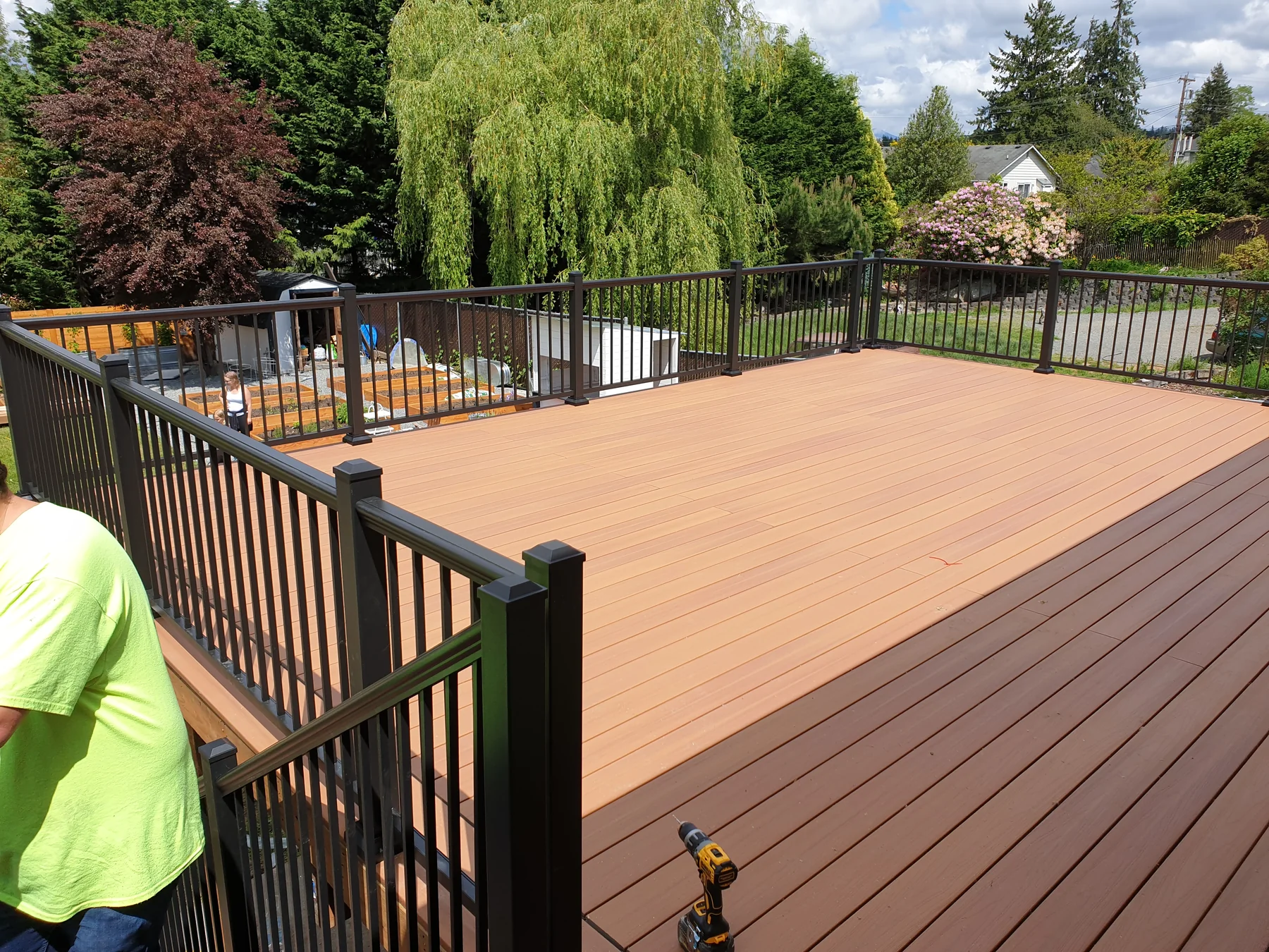 Finished composite deck with dark metal railing in a landscaped backyard