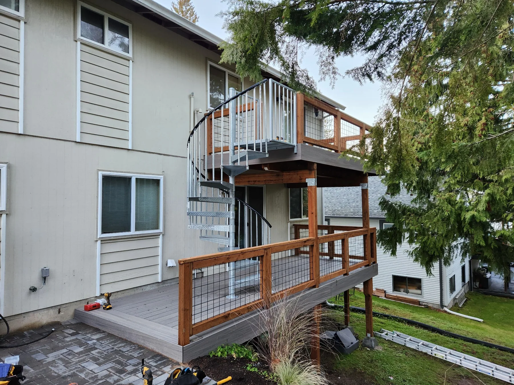 Two-story deck addition with wood posts and metal cable-style railings